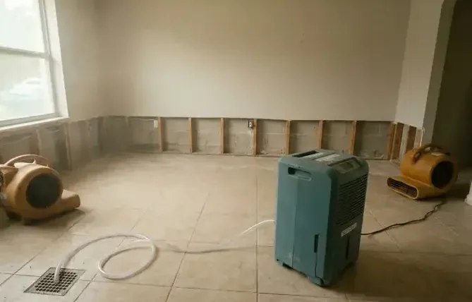 Dehumidifier and air movers drying a room after baseboards were removed